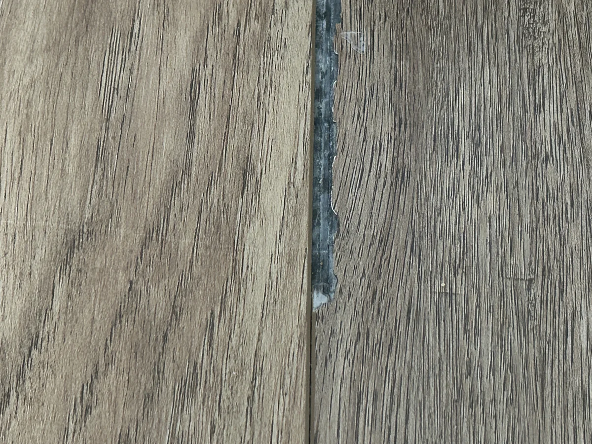 Close view of a fractured rigid-core plank edge and exposed core