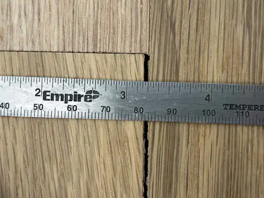 Visible hardwood board gap photographed during an independent floor inspection
