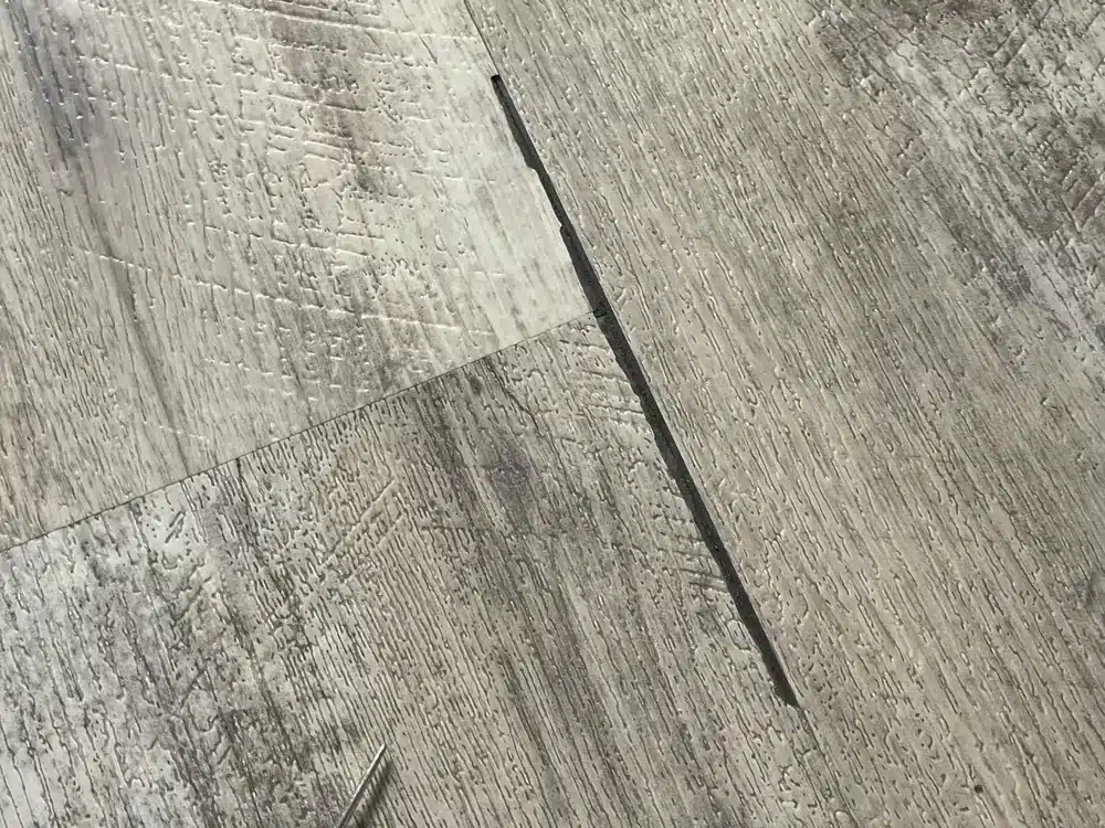 Broken rigid-core flooring edge documented at the property
