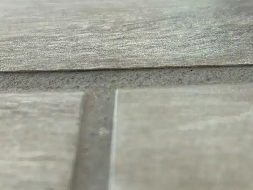 Low grout joint exposing an adjacent tile edge